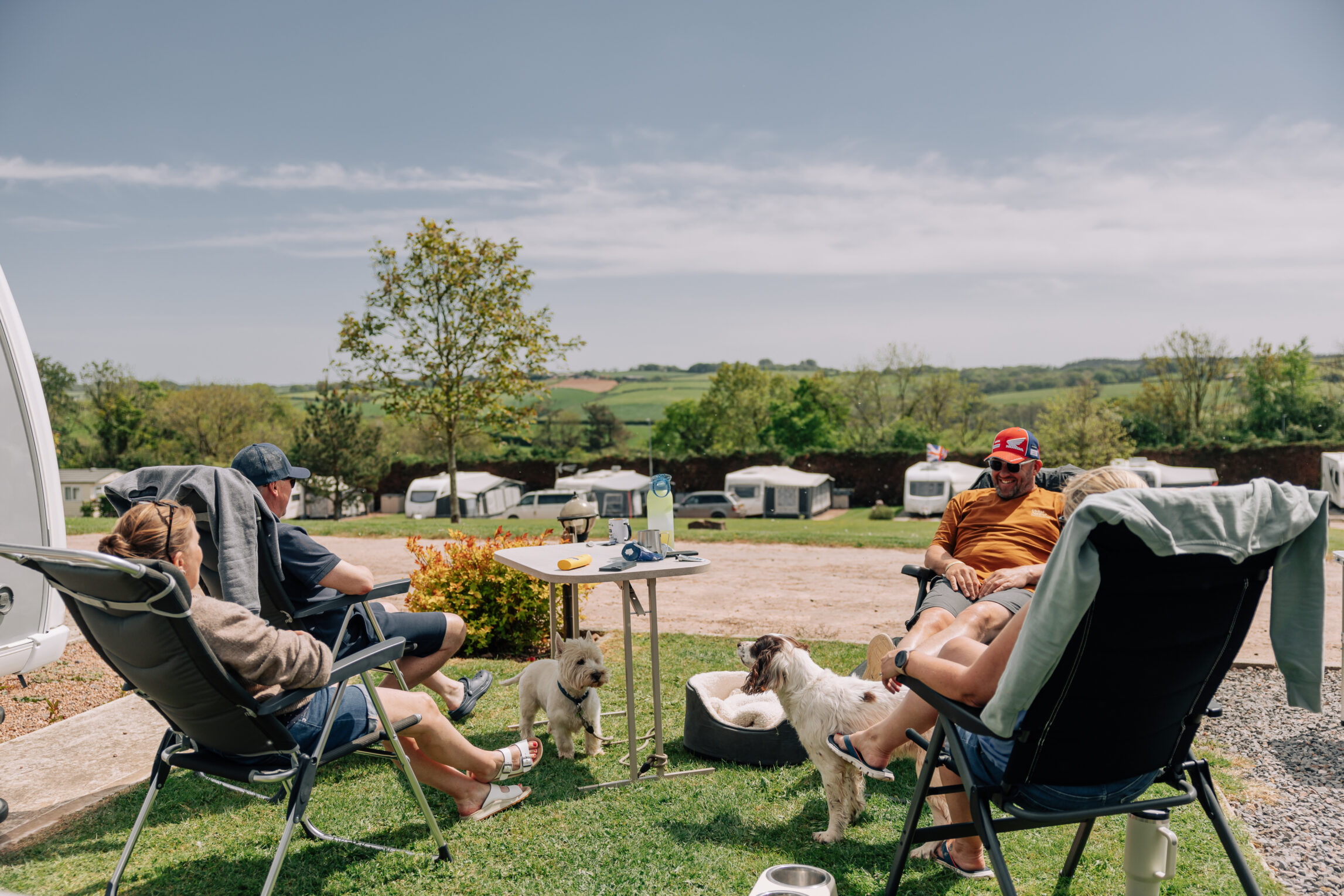 family sitting on camping chairs outside a caravan at yeatheridge