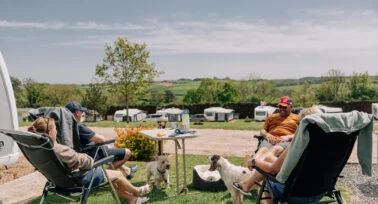 family sitting on camping chairs outside a caravan at yeatheridge